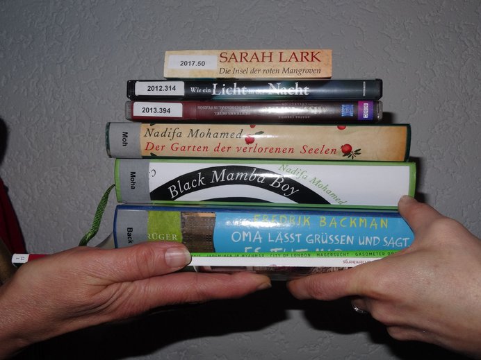 zwei Menschen tauschen einen Stapel Bücher aus