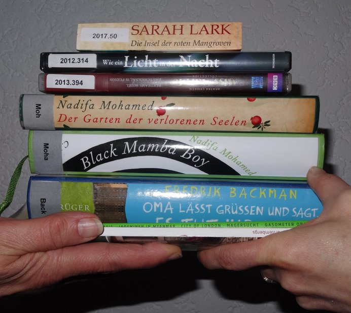 zwei Menschen tauschen einen Stapel Bücher aus